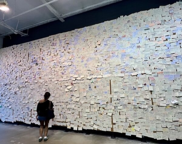 A visitor reading the wall of handwritten notes at the Reading Room in Washington, D.C.